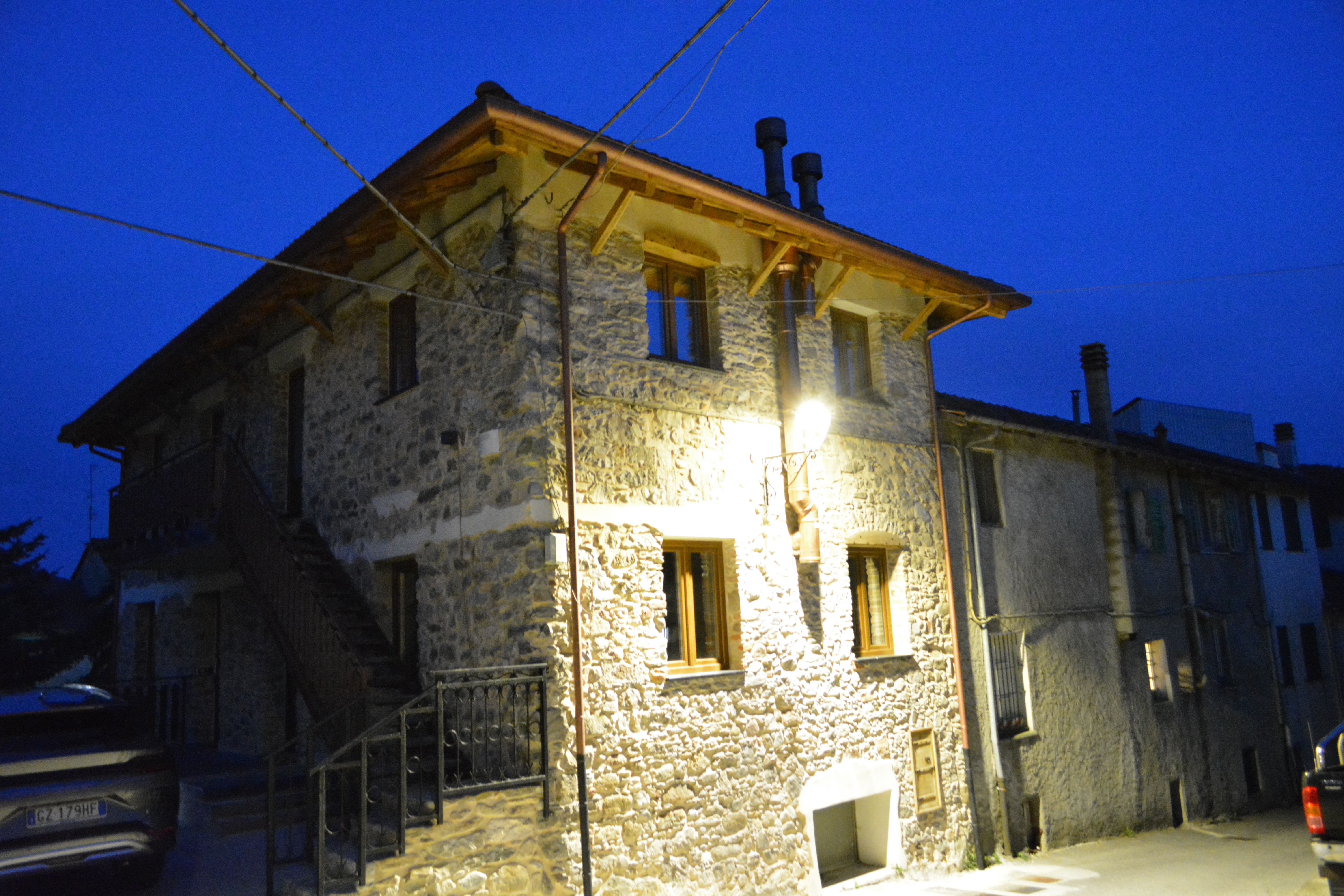 La cascina restaurata in pietra, illuminata all'imbrunire